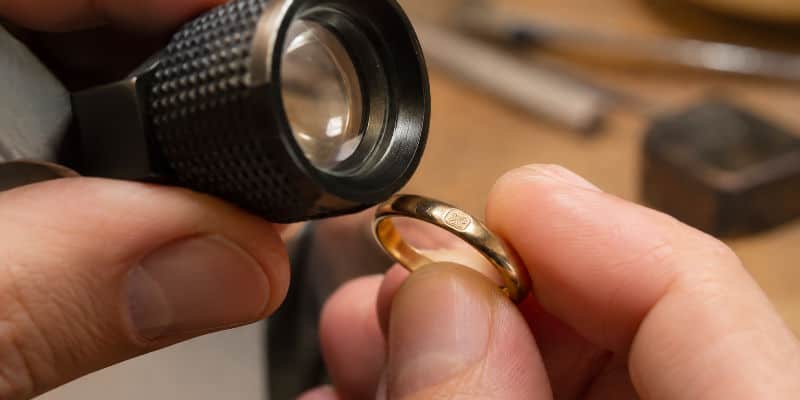 Examen à la loupe d'un poinçon sur un bijou en or
