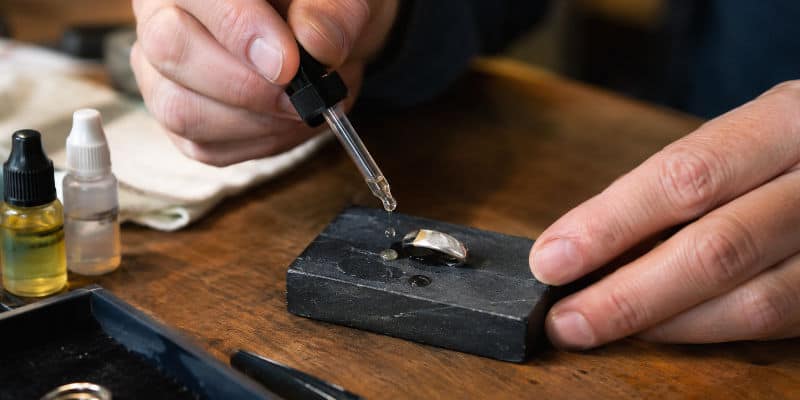 Test de pureté de l'argent réalisé sur une pierre de touche par un professionnel